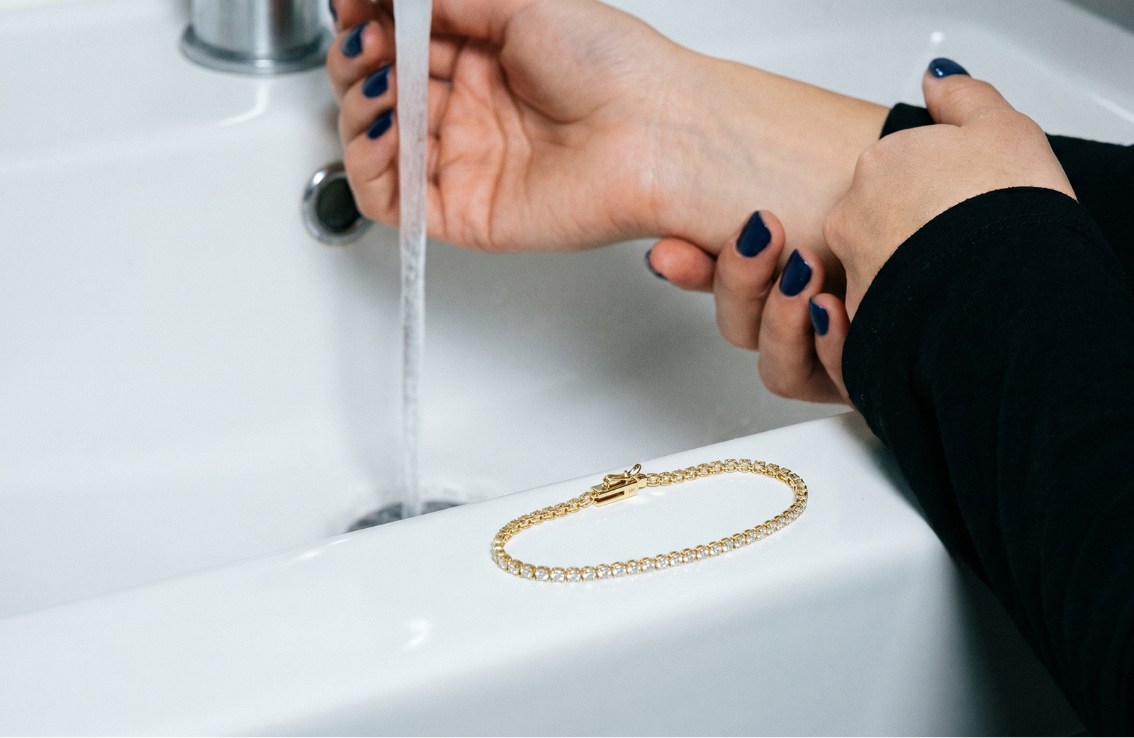 Solid gold diamond tennis bracelet resting on a sink edge